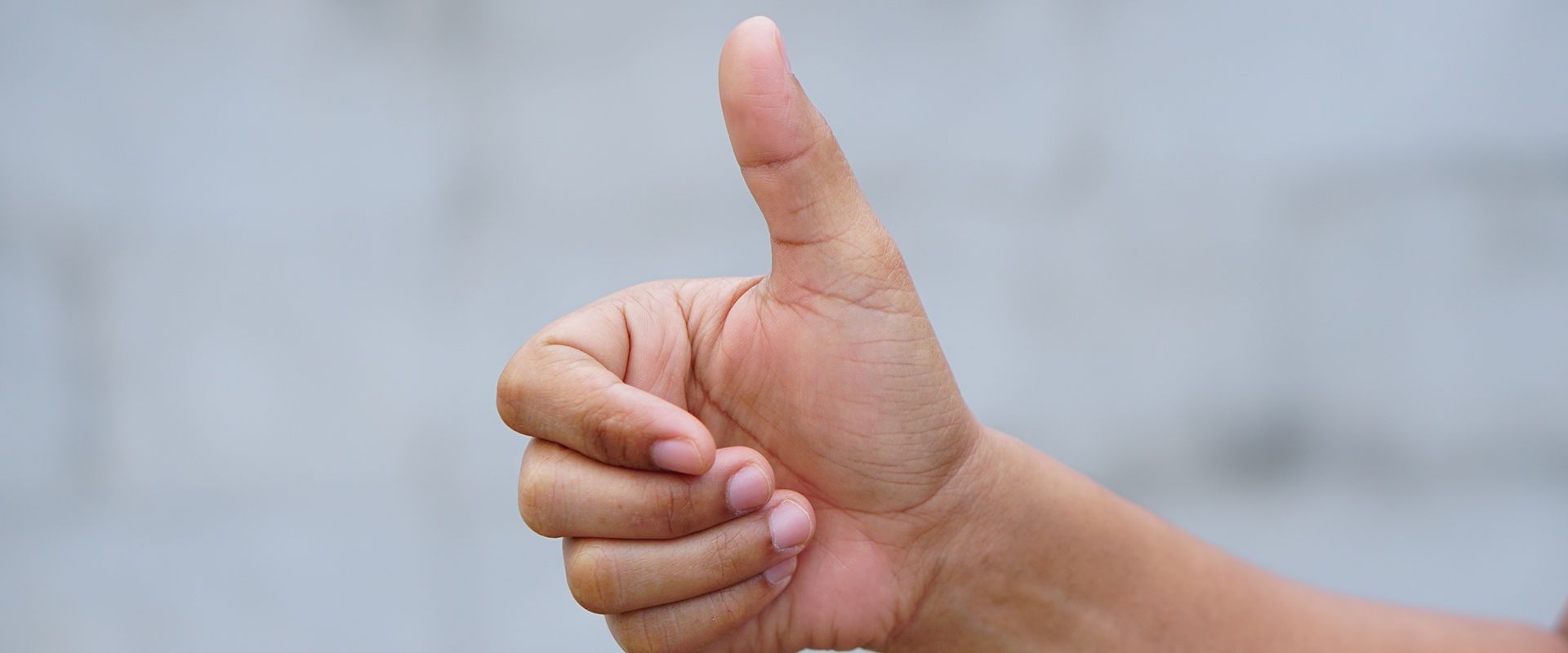 Hand mit nach oben gestrecktem Daumen