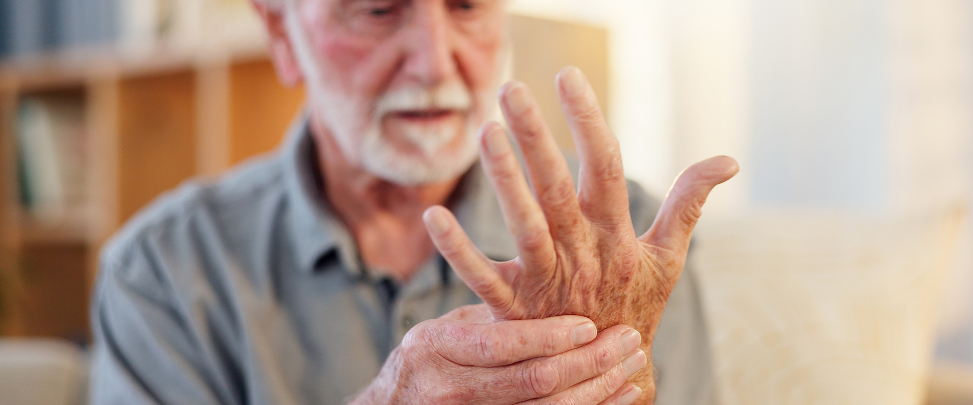Mann schaut seine  schmerzende Hand an