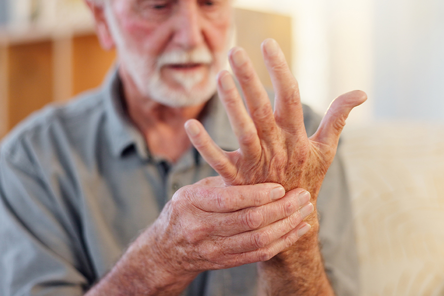 Mann schaut seine  schmerzende Hand an