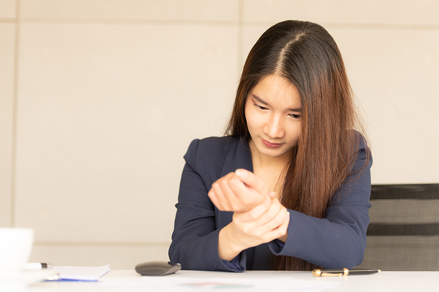 Frau betrachtet ihr schmerzendes Handgelenk