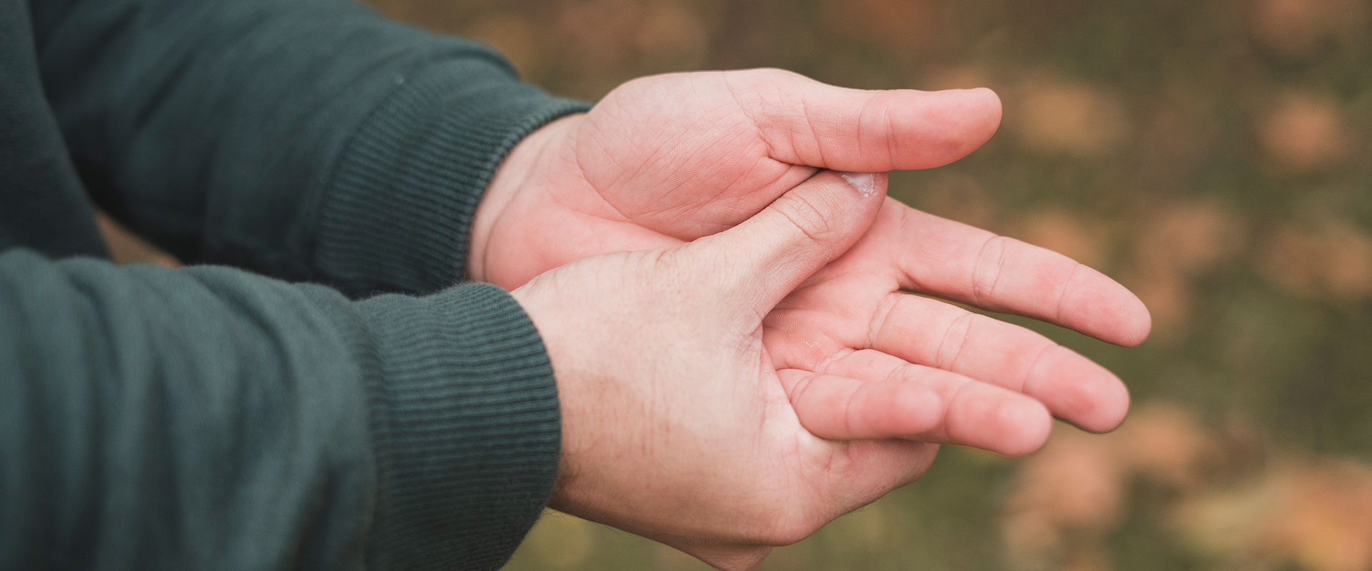 Mann drückt seinen Daumen auf seine schmerzende Hand